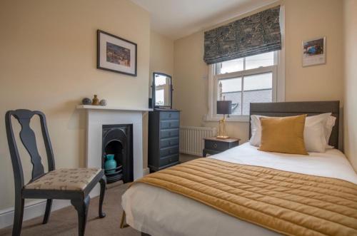 a bedroom with a bed and a chair and a fireplace at 107 and 109 Nunnery Lane in York