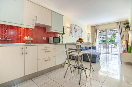 una cucina con mobili bianchi, tavolo e sedie di El Dorado Garden View PH04 ad Arona