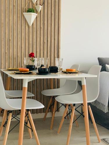 a dining room table with white chairs and a white table at Apartament w Słupsku z klimatyzacją balkonem parkingiem in Słupsk