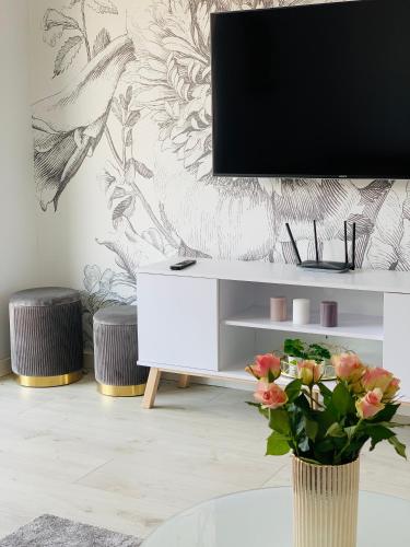 a living room with a tv and a vase with flowers at Apartament w Słupsku z klimatyzacją balkonem parkingiem in Słupsk