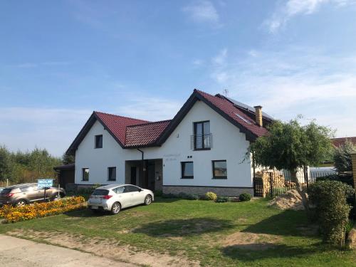 a white house with a car parked in the yard at Apartamenty i Pokoje Na Letniej in Darłowo