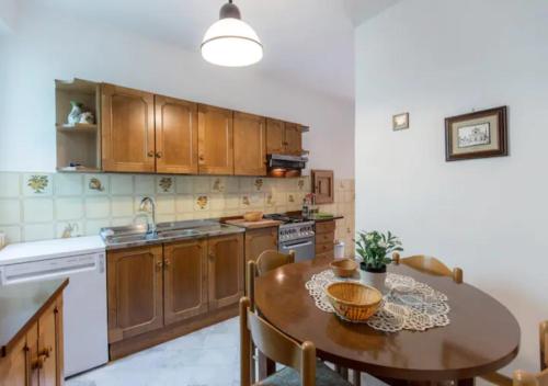 una cocina con armarios de madera, mesa y fregadero en Lungarno Vespucci Charming Apartment, en Florencia