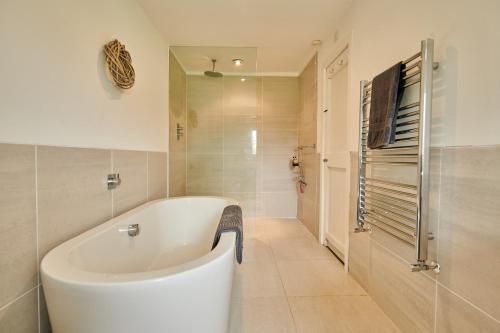 a white bathroom with a tub and a shower at Wildhaven- Idylic rural farmhouse with log burner and countryside views in Gwynfe