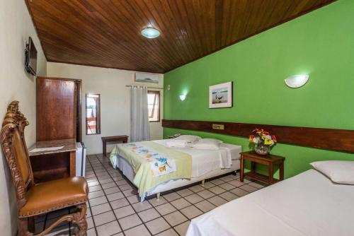 a bedroom with a bed and a green wall at Hotel Costa Verde in Porto Seguro