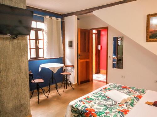 a bedroom with a bed and a table and chairs at Chalé de Charme Mandomai in Ilhabela