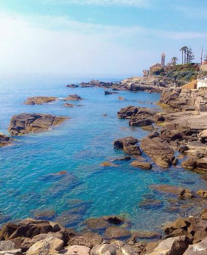 a rocky beach with blue water and rocks at New Agriloft 4 Palms clima, giardino e Wi-Fi a 50 mt dal mare in Bordighera