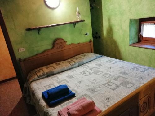 a bed in a green room with two towels on it at Casa vacanze La Carbunera in Domodossola