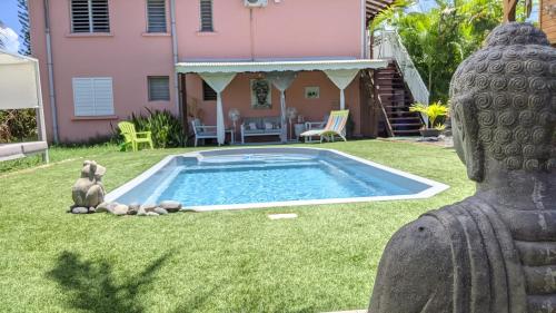 a statue in the yard of a house with a pool at Villa Rosa Karibella in Saint-François