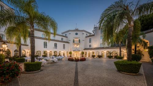 a large building with palm trees in a courtyard at Las Dunas Grand Luxury in Estepona