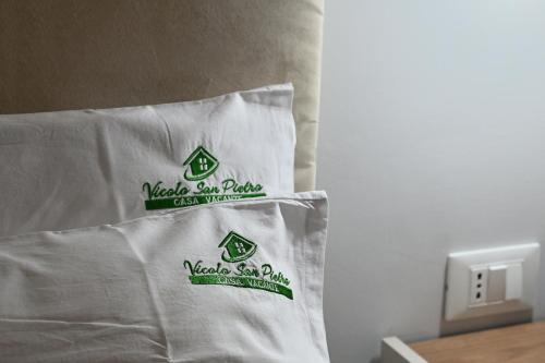a bed with white sheets with green labels on it at Casa Vacanze Vicolo San Pietro in Agrigento