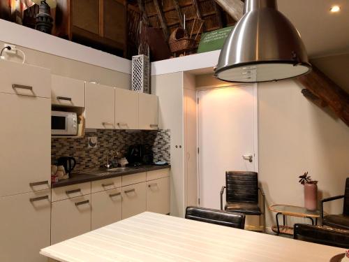 een keuken met witte kasten en een tafel bij Hoeve te Gast - vakantieboerderij in Groet