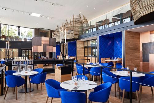 a dining room with blue chairs and tables at Cottage "Les MARAIS" à quelques pas du Lac de la forêt d'Orient - Les Cottages du Belvédère in Mesnil-Saint-Père