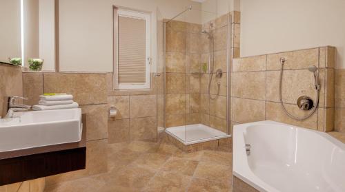 a bathroom with a shower and a sink and a tub at Hotel Villa Toskana in Leimen
