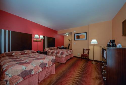 a hotel room with two beds and a dresser at Rodeway Inn MacArthur Airport in Ronkonkoma
