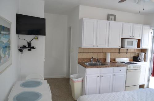 a small kitchen with white cabinets and a sink at Tiana Beach Inn in Hollywood Beach