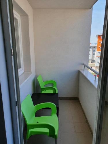 three green chairs in a room with a balcony at Ognjen Apartman in Donje Mladice