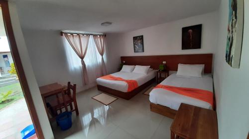 a hotel room with two beds and a window at HOSTAL TERO REAL in Puerto Villamil