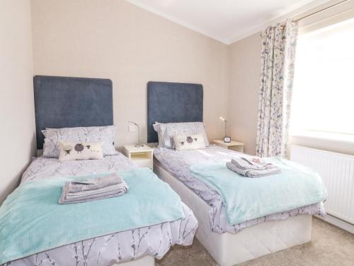 two beds in a bedroom with blue and white at Stonesthrow in Grantham
