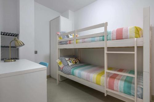 Habitación blanca con 2 literas y escritorio. en Apartamento ideal en Manresa, en Manresa