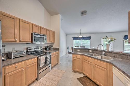 a large kitchen with wooden cabinets and a sink at Ranch-Style Lehigh Acres House with Big Backyard! in Lehigh Acres