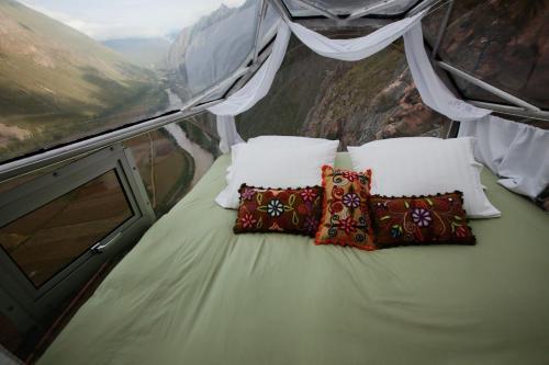 1 cama con almohadas en la cima de una montaña en Skylodge Adventure Suites en Urubamba