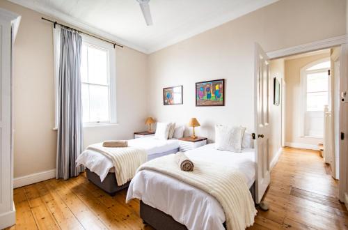 Duas camas num quarto com paredes brancas e pisos em madeira em Fintimara Beach House em Kalk Bay