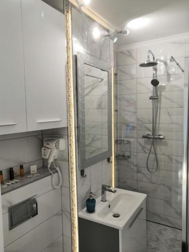 a white bathroom with a sink and a shower at ONYX - Utopia Aparthotel in Braşov