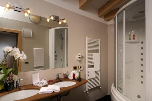 a bathroom with a sink and a shower and a mirror at Hotel La Perla Wellness & Beauty in Canazei