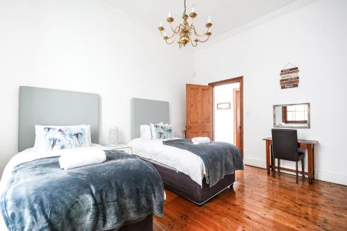 1 dormitorio con 2 camas, escritorio y lámpara de araña en Oceanfront Penthouse, en Muizenberg