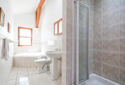 a bathroom with a toilet and a shower and a sink at Oceanfront Penthouse in Muizenberg
