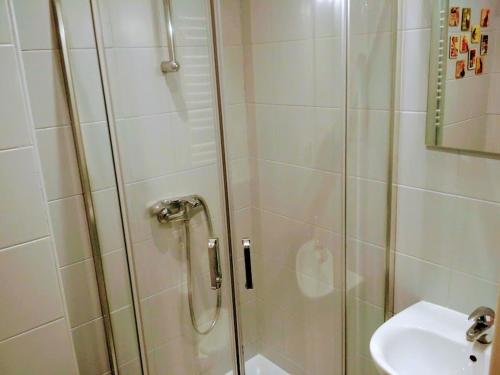 una ducha con una puerta de cristal junto a un lavabo en Silver Wolf Bosacka, en Cracovia