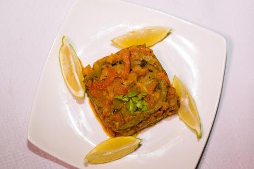 a white plate with a piece of food with lemon slices at RIAD TUMAST in Aït Slimane
