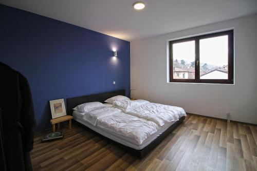 a bedroom with a bed with a blue wall and a window at Blue apartment over Prizren roofs in Prizren