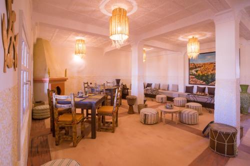 a dining room with a table and chairs and a couch at RIAD TUMAST in Aït Slimane