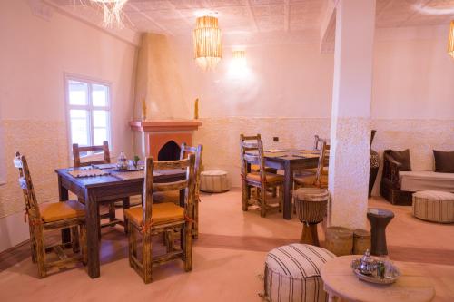 a dining room with tables and chairs and a fireplace at RIAD TUMAST in Aït Slimane