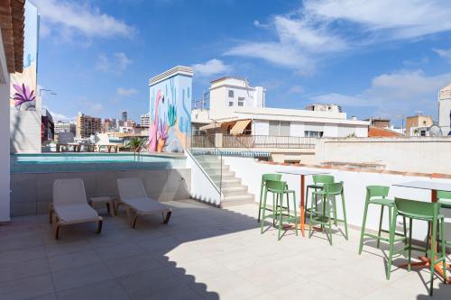 a rooftop patio with tables and chairs and a pool at Apartamentos Mayal con Piscina in Benidorm