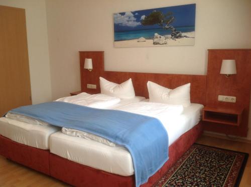 a bedroom with a large bed with a blue blanket at Pension Altstadt Garni in Bad Windsheim