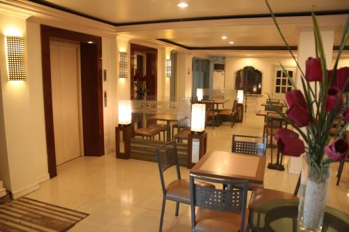 Un restaurante con mesas y sillas y un jarrón de flores. en De Luxe Hotel, en Cagayan de Oro