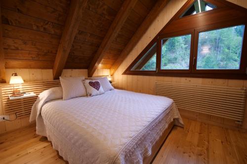1 dormitorio con 1 cama en una cabaña de madera en CHALET PRATI OGRCA, en Valbruna