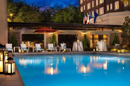 a swimming pool at night with tables and chairs at Warwick Melrose Hotel in Dallas