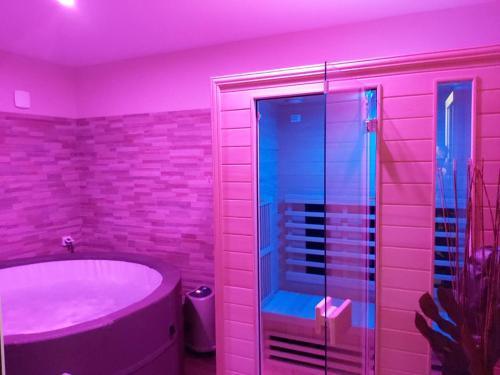 un bagno rosa con vasca e doccia in vetro di Chambre d'hôtes SOPHORA - Les Clés des Lys a Moret-sur-Loing
