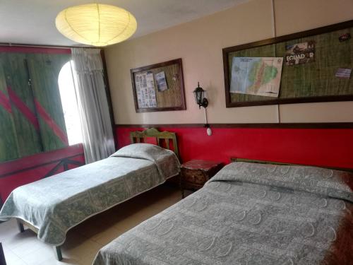 two beds in a room with red walls at Flying Donkey in Otavalo