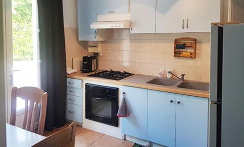 La cuisine est équipée de placards bleus et d'un four avec plaques de cuisson. dans l'établissement maison calme et paisible, à La Faye