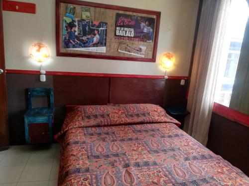 a bedroom with a bed and two lights on the wall at Flying Donkey in Otavalo
