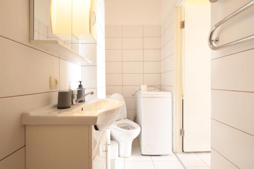La salle de bains blanche est pourvue de toilettes et d'un lavabo. dans l'établissement "Deluxe Apartments" on Kulisha 45 - 1128, à Lviv