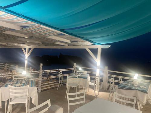 una terraza con mesas y sillas blancas por la noche en Oldwell Hotel, en Tropea
