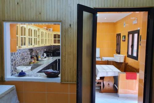 une cuisine avec des murs orange, des tables et des armoires dans l'établissement Large House in Tangiers with Garage, à Tanger