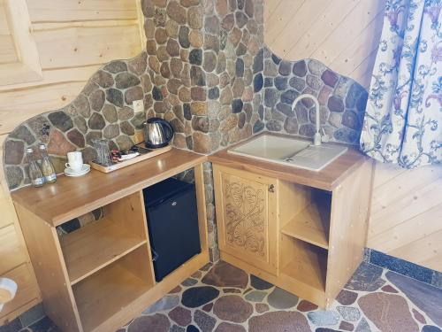 a kitchen with a sink and a stone wall at Chata Góralska i Pokoje Gościnne in Ciechocinek