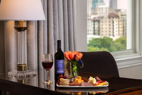 a table with a plate of food and a glass of wine at Warwick Melrose Hotel in Dallas