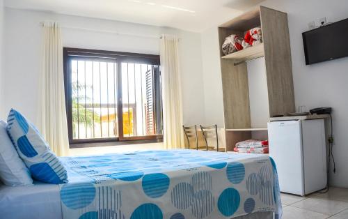een slaapkamer met een bed en een groot raam bij Classe Pousada in Imbé